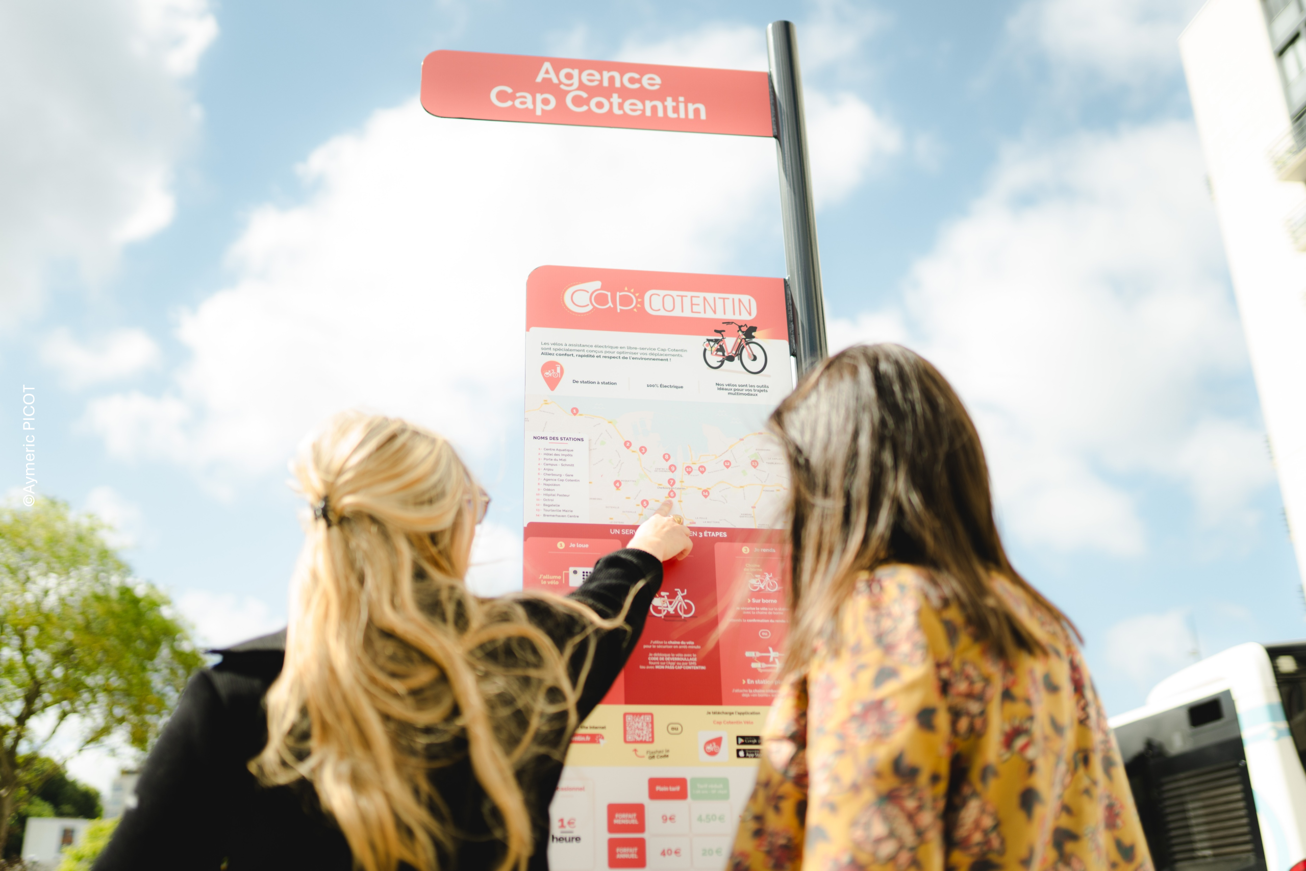 Deux usagers des vélos en libre-service de Cherbourg en Cotentin regarde les modalités d'inscription au service sur le totem d'information à la station Napoléon.